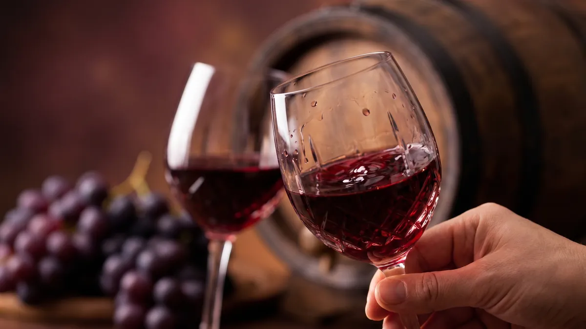 Ly rượu vang đỏ Cabernet Sauvignon Chile sóng sánh bên thùng gỗ sồi